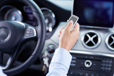 Eine Frau sitzt in einem Auto und hält einen 4-Kanal-Handsender TX4REV-F in der Hand